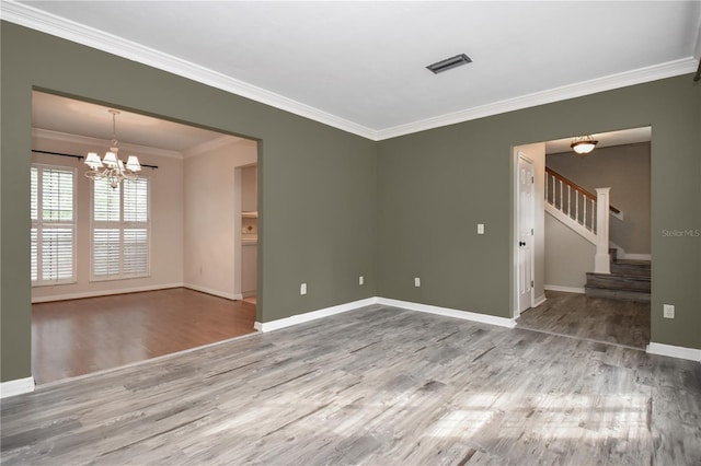 spare room with hardwood / wood-style flooring, ornamental molding, and a chandelier