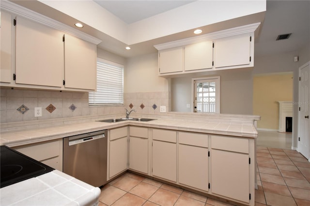 kitchen featuring sink, stainless steel dishwasher, kitchen peninsula, tile countertops, and light tile patterned flooring