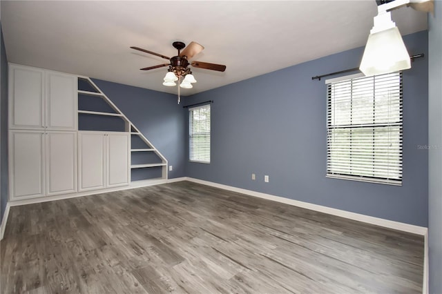 empty room with ceiling fan, plenty of natural light, and wood-type flooring