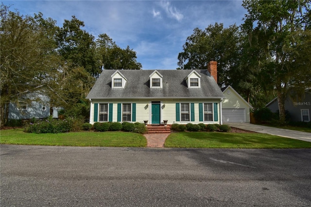 new england style home featuring a garage, an outbuilding, and a front yard