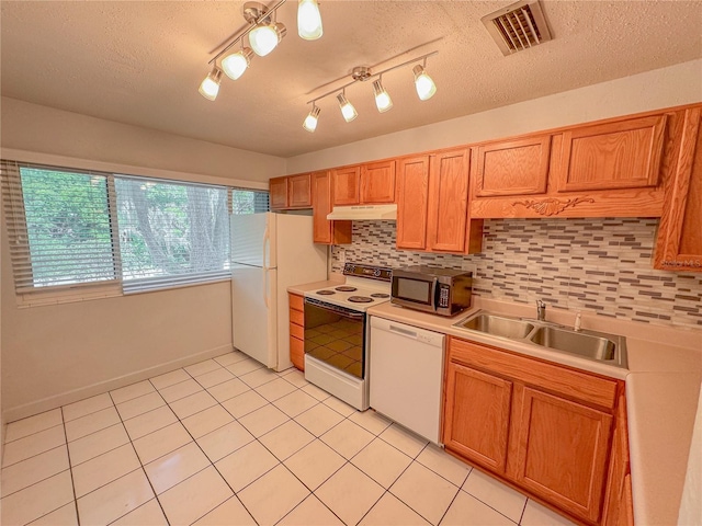 kitchen featuring backsplash, sink, white appliances, and light tile flooring