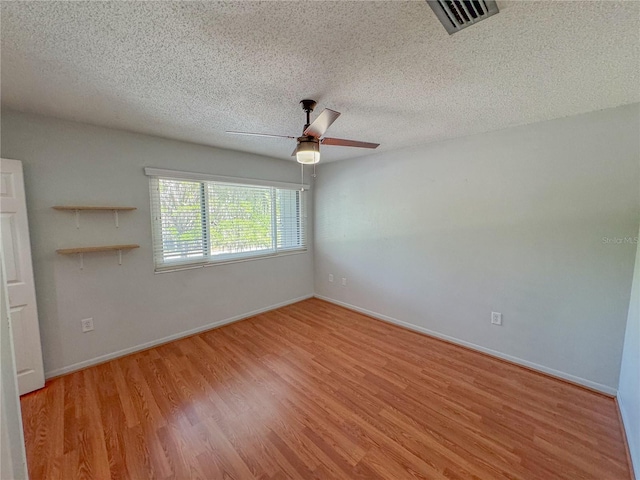 unfurnished room with ceiling fan, a textured ceiling, and light wood-type flooring