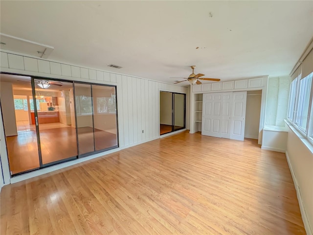 empty room with a healthy amount of sunlight, ceiling fan, and light hardwood / wood-style flooring