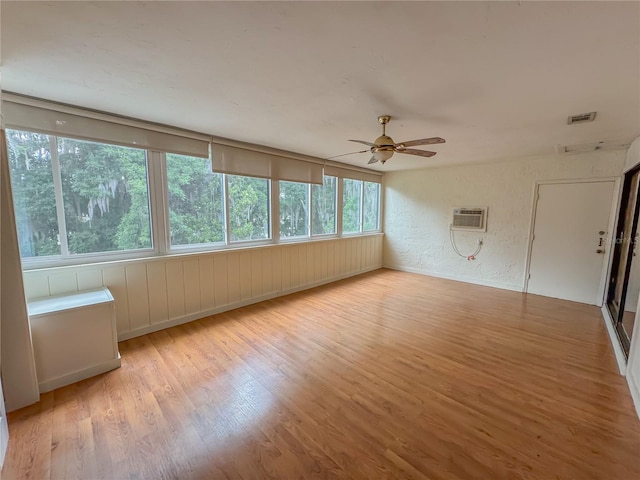 unfurnished room featuring an AC wall unit, ceiling fan, and light wood-type flooring