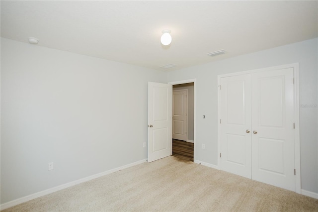 unfurnished bedroom with light colored carpet and a closet