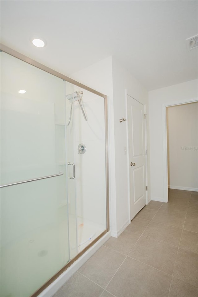 bathroom with a shower with shower door and tile floors