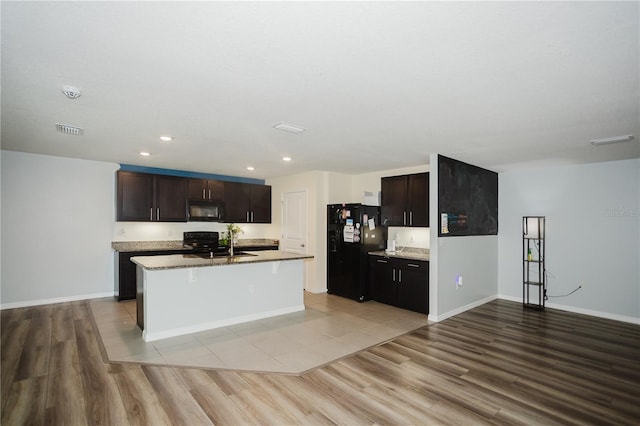 kitchen featuring hardwood / wood-style floors, black appliances, an island with sink, dark brown cabinets, and sink