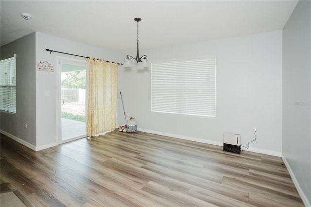 unfurnished room with an inviting chandelier and wood-type flooring