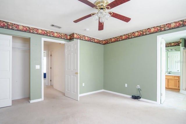 unfurnished bedroom featuring carpet flooring, a closet, ceiling fan, and ensuite bath