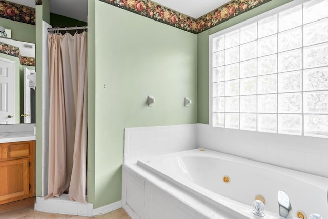 bathroom with tile floors, a relaxing tiled bath, plenty of natural light, and vanity