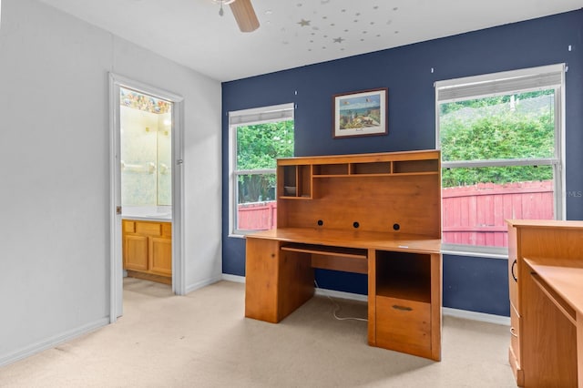 office area featuring light carpet, plenty of natural light, ceiling fan, and built in desk