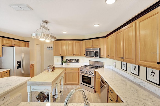 kitchen with light hardwood / wood-style floors, pendant lighting, light stone counters, and stainless steel appliances