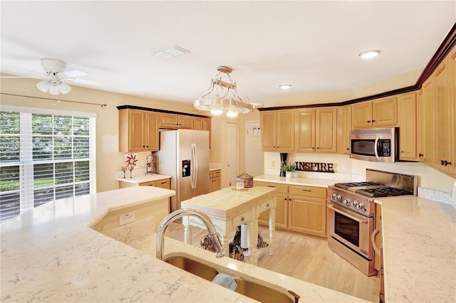 kitchen with light hardwood / wood-style floors, appliances with stainless steel finishes, pendant lighting, sink, and ceiling fan