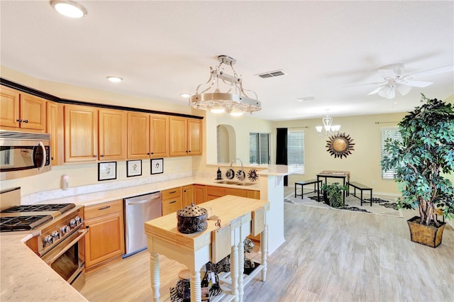 kitchen featuring light hardwood / wood-style floors, stainless steel appliances, pendant lighting, ceiling fan with notable chandelier, and sink