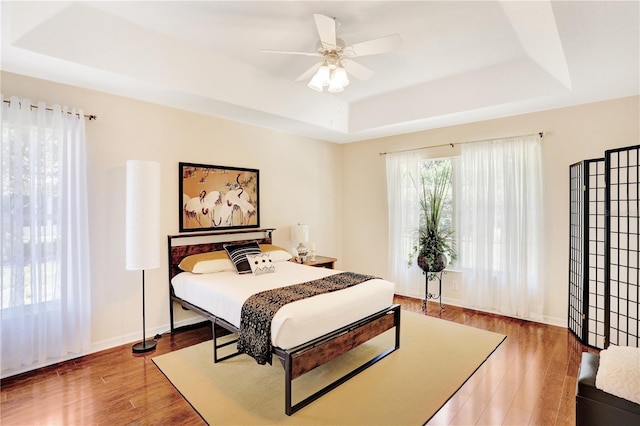 bedroom featuring ceiling fan, hardwood / wood-style flooring, and a raised ceiling