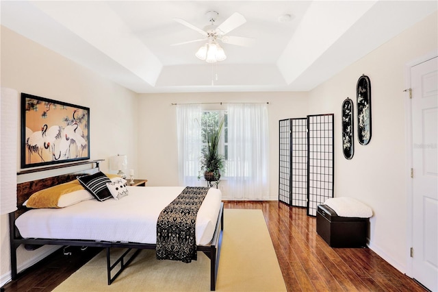 bedroom featuring wood-type flooring, ceiling fan, and a raised ceiling