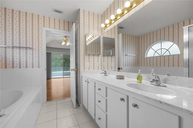 bathroom featuring vanity, a healthy amount of sunlight, tile patterned floors, and tiled tub