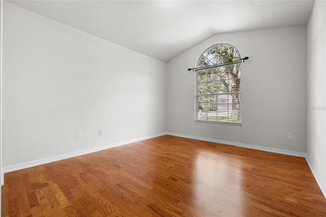 spare room with lofted ceiling and hardwood / wood-style flooring