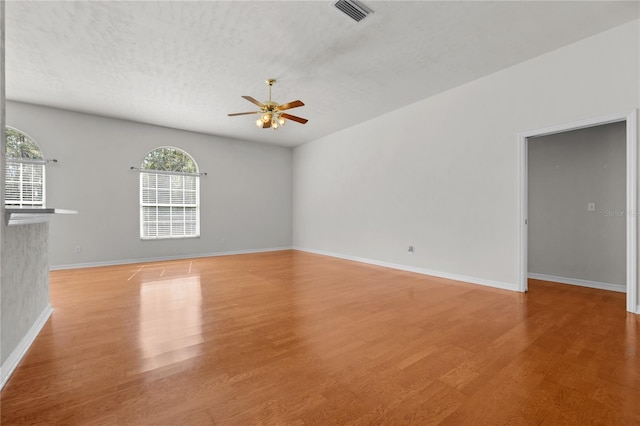 unfurnished living room featuring light hardwood / wood-style flooring, a textured ceiling, ceiling fan, and plenty of natural light