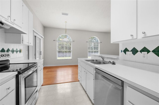 kitchen featuring stainless steel appliances, white cabinetry, decorative light fixtures, decorative backsplash, and sink