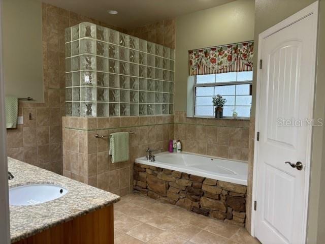 bathroom featuring a relaxing tiled bath, vanity, and tile floors