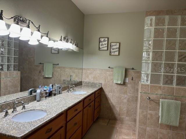 bathroom featuring tile walls, tile floors, oversized vanity, and dual sinks