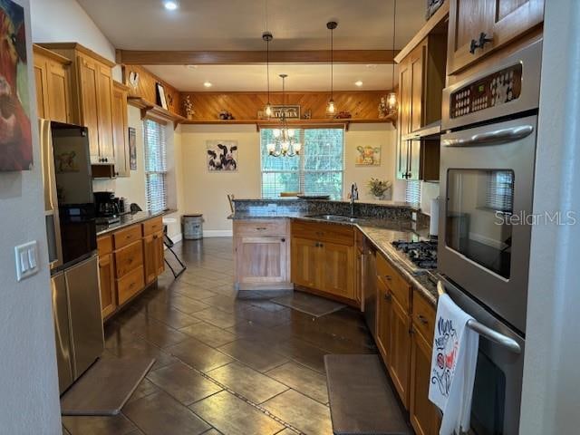 kitchen with stainless steel appliances, decorative light fixtures, dark tile flooring, sink, and a chandelier