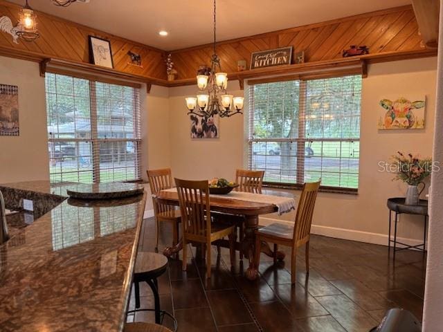 dining space featuring a healthy amount of sunlight, wood walls, and a chandelier