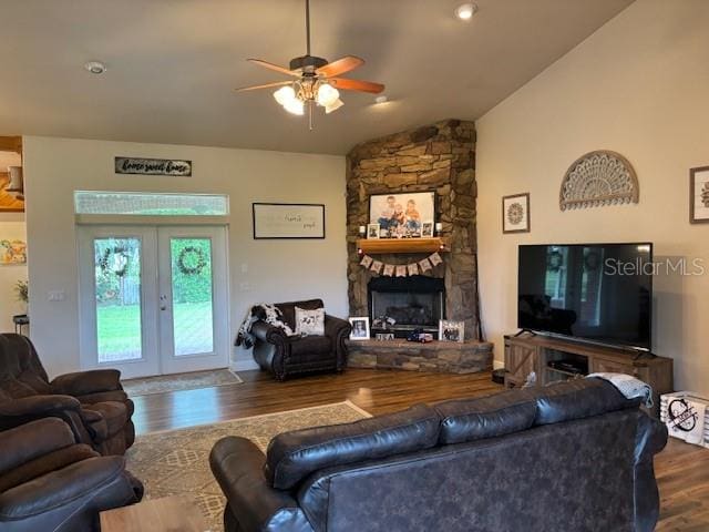 living room featuring a stone fireplace, ceiling fan, french doors, wood-type flooring, and lofted ceiling