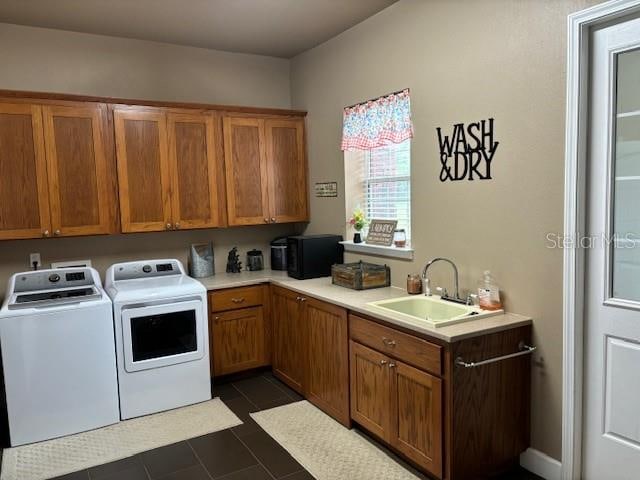 clothes washing area with sink, dark tile flooring, independent washer and dryer, and cabinets