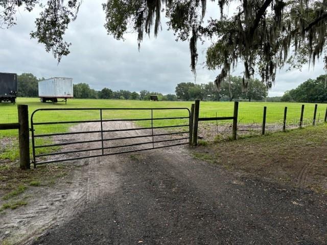 view of gate featuring a rural view and a lawn