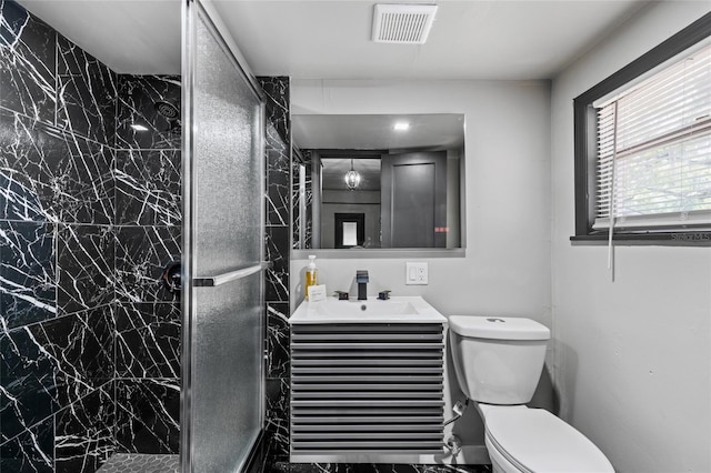 bathroom with vanity, toilet, and a tile shower