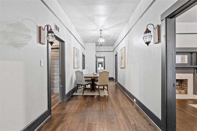 hallway featuring a notable chandelier and dark hardwood / wood-style flooring