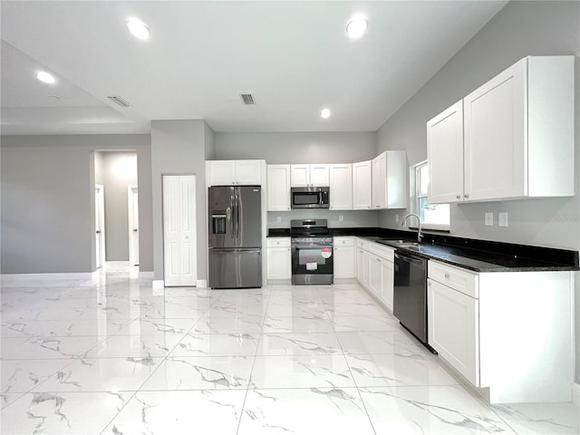 kitchen with light tile flooring, dark stone countertops, white cabinets, sink, and appliances with stainless steel finishes