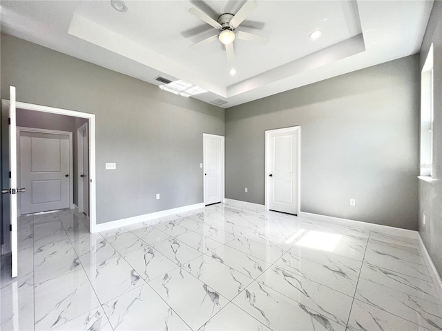 spare room featuring ceiling fan, a raised ceiling, and light tile floors