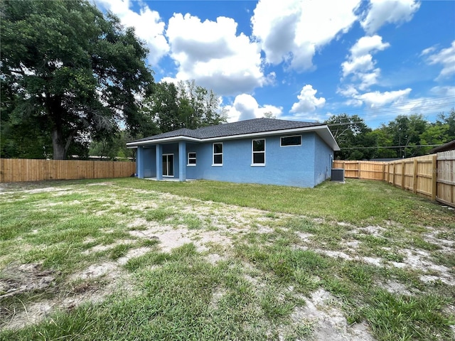 rear view of property featuring a lawn and central air condition unit