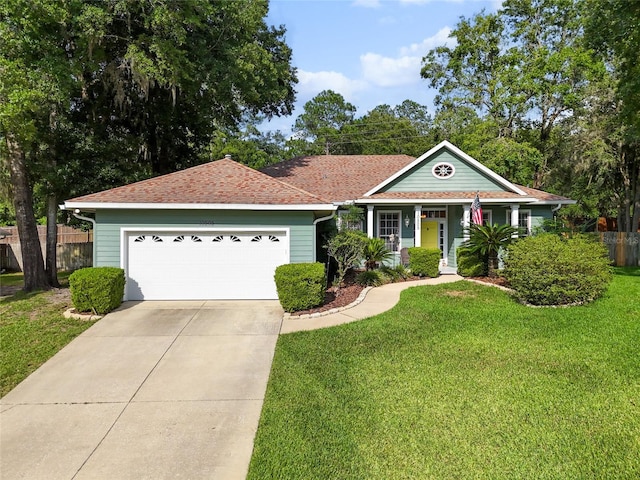 single story home featuring a porch, a garage, and a front lawn