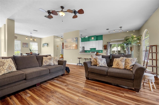 living room with track lighting, light hardwood / wood-style floors, ceiling fan, and plenty of natural light