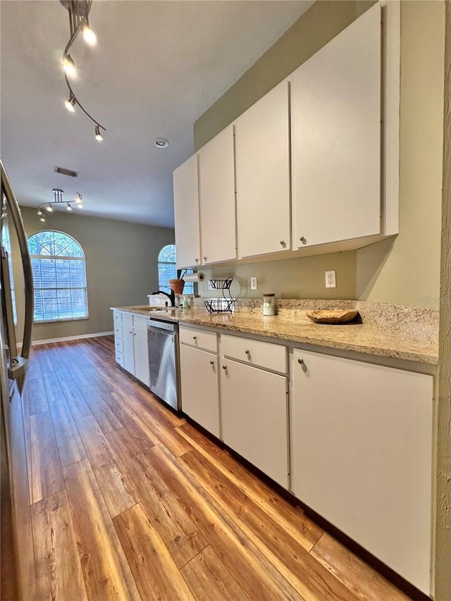 kitchen featuring appliances with stainless steel finishes, white cabinetry, sink, light stone counters, and light hardwood / wood-style flooring