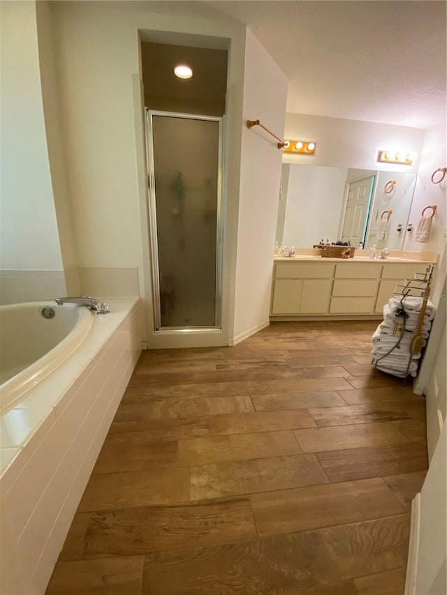 bathroom with hardwood / wood-style floors, vanity, and plus walk in shower