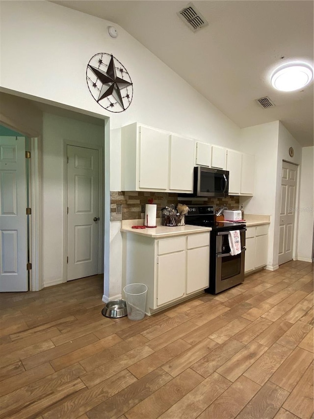 kitchen with white cabinetry, stainless steel appliances, tasteful backsplash, light hardwood / wood-style floors, and lofted ceiling