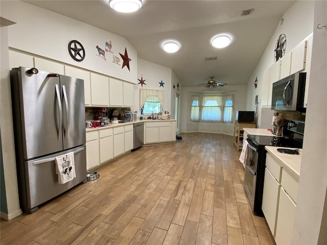 kitchen with stainless steel appliances, ceiling fan, white cabinets, light hardwood / wood-style floors, and lofted ceiling