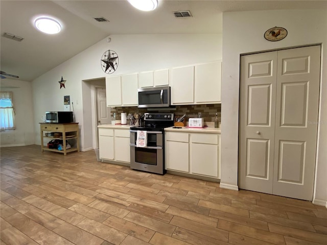 kitchen featuring white cabinets, stainless steel appliances, light hardwood / wood-style flooring, and lofted ceiling