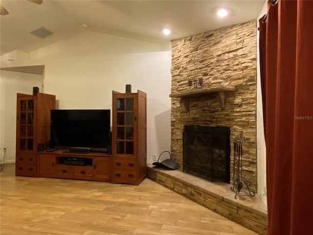 living room with a fireplace, light wood-type flooring, ceiling fan, and lofted ceiling