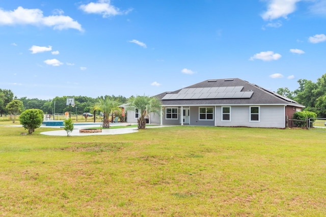 rear view of property with a yard and solar panels