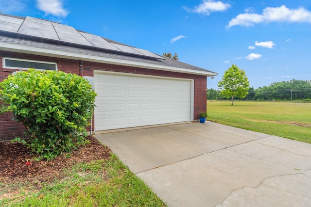 garage featuring solar panels and a lawn