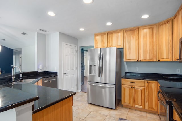 kitchen with kitchen peninsula, stainless steel appliances, sink, dark stone countertops, and light tile patterned flooring