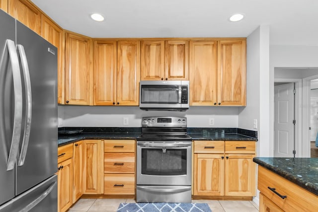 kitchen with dark stone countertops, light tile patterned flooring, and appliances with stainless steel finishes