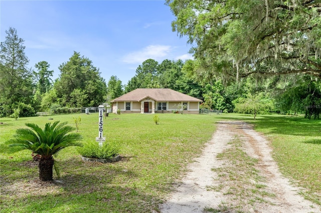 ranch-style house with a front yard, dirt driveway, and stucco siding