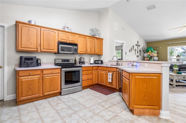 kitchen featuring lofted ceiling, stainless steel appliances, kitchen peninsula, and sink